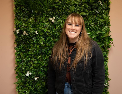 Gracelyn standing in front of a greenery wall