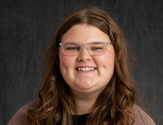 Randi smiling at the camera with a gray background